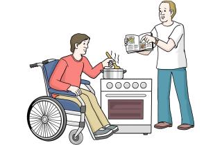 Ein Mann, der im Rollstuhl sitzt, kocht an einem Herd eine Mahlzeit. Eine Hilfskraft steht neben ihm und hält ein Kochbuch. Die Hilfskraft hilft dem Mann beim Kochen.