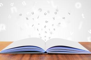 Aus einem geöffneten Buch fliegen Buchstaben raus.