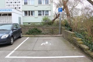Behindertenparkplatz vor einem Wohnhaus.