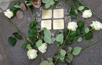 Gedenktafeln im Boden mit dazugelegten Rosen.