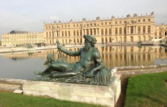 Bronze-Skulpur vor Park-Teichanlage. Im Hintergrund befindet sich das Schloss Versailles.
