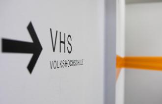 Ein Wegweiser mit Pfeil im Treppenhaus der VHS.
