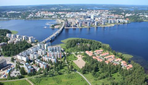 Jyväskylä Luftbild der Stadt Jyväskylä mit Häusern, Wiesen und Brücke über einem Fluss.